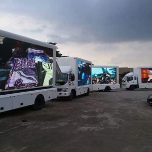 A fleet of Mobile LED Advertising Trucks in Abuja featuring vibrant, illuminated screens displaying promotional content in a parking area.